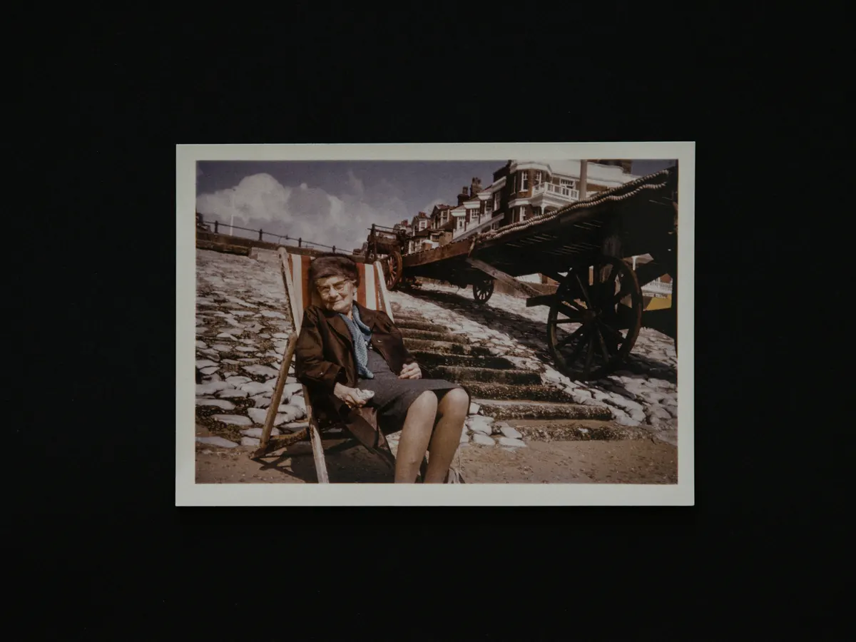 A single faded color print of an older woman in a deckchair, laid on a dark table.