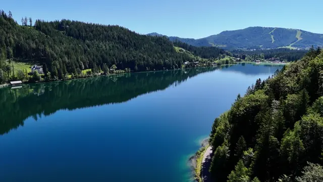 Aerial view drifting over a blue alpine lake ringed by forest